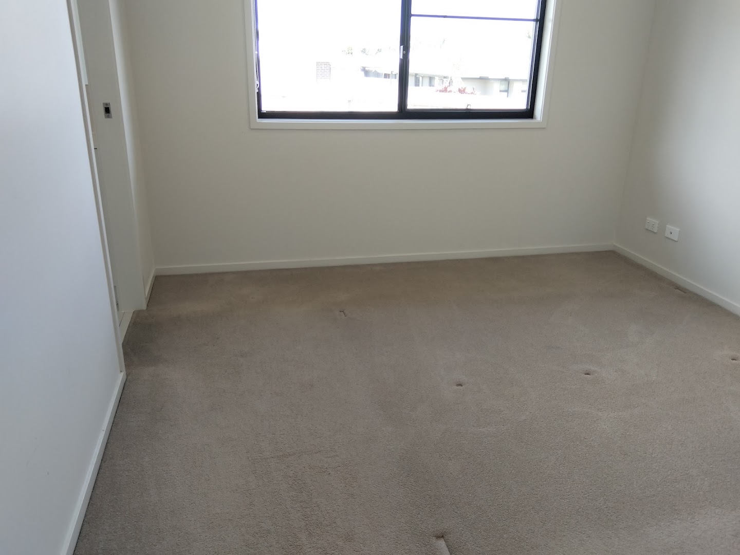 An empty carpeted room lit by a single window