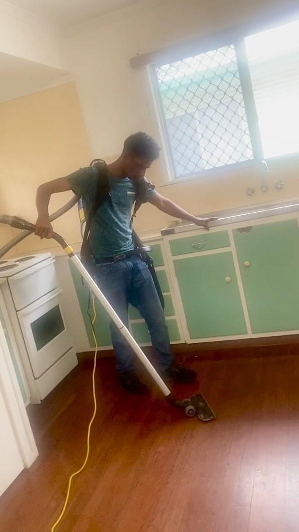 A cleaner running a floor machine across polished timber boards in an empty kitchen