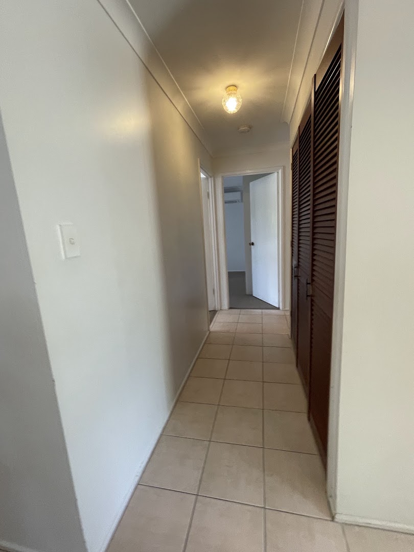 An empty tiled hallway with doors opening off both sides