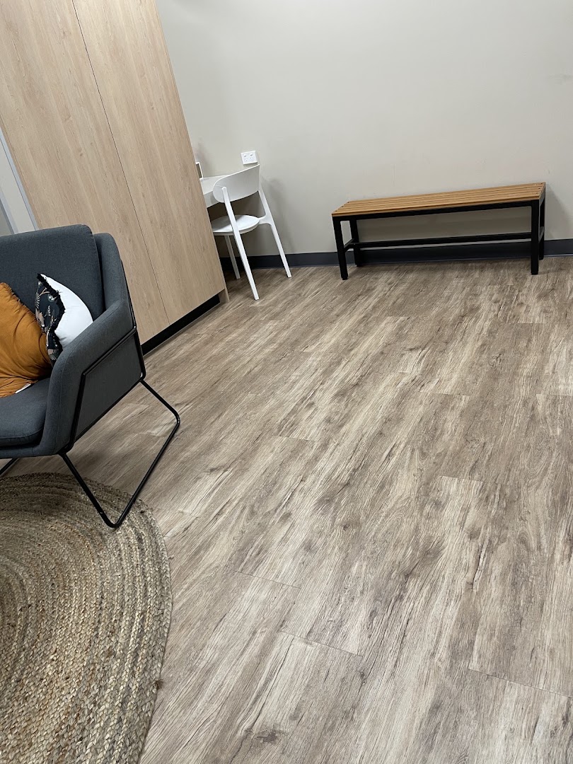 An empty room with a plank floor and a single armchair by the window