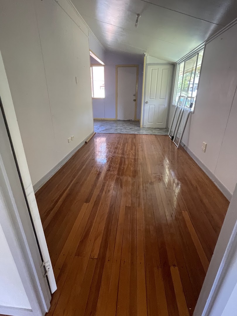 A hallway with polished timber boards running to an open doorway