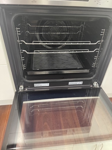 An open oven with the racks out and the door glass clear