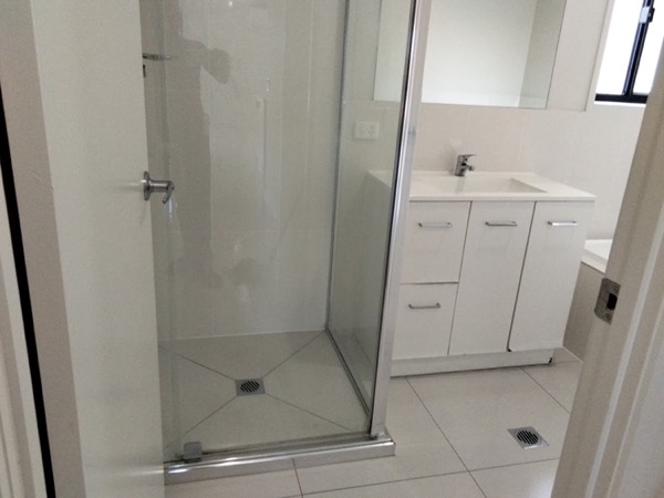A glass shower screen and a white vanity in a tiled bathroom