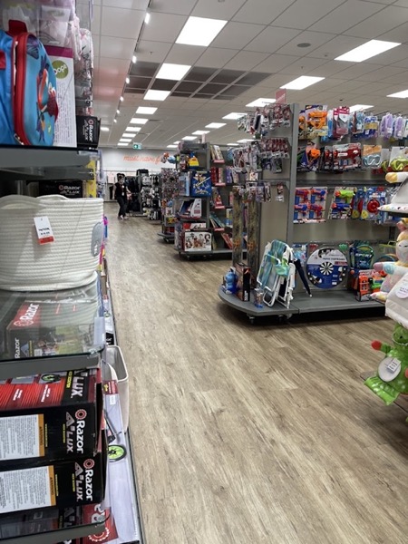 A retail aisle with a plank floor and stocked shelving on both sides