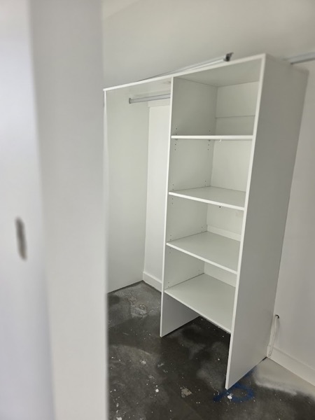 An empty white wardrobe with shelves and a hanging rail
