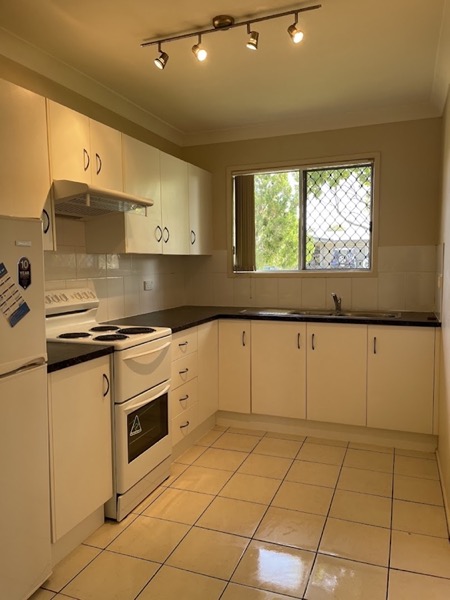 A kitchen with a tiled floor, timber-look cupboards and a window