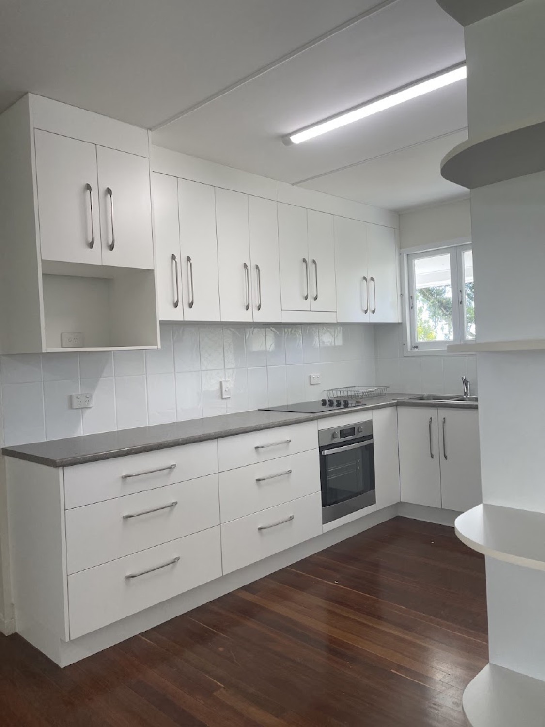 A white kitchen with overhead cupboards and a timber floor