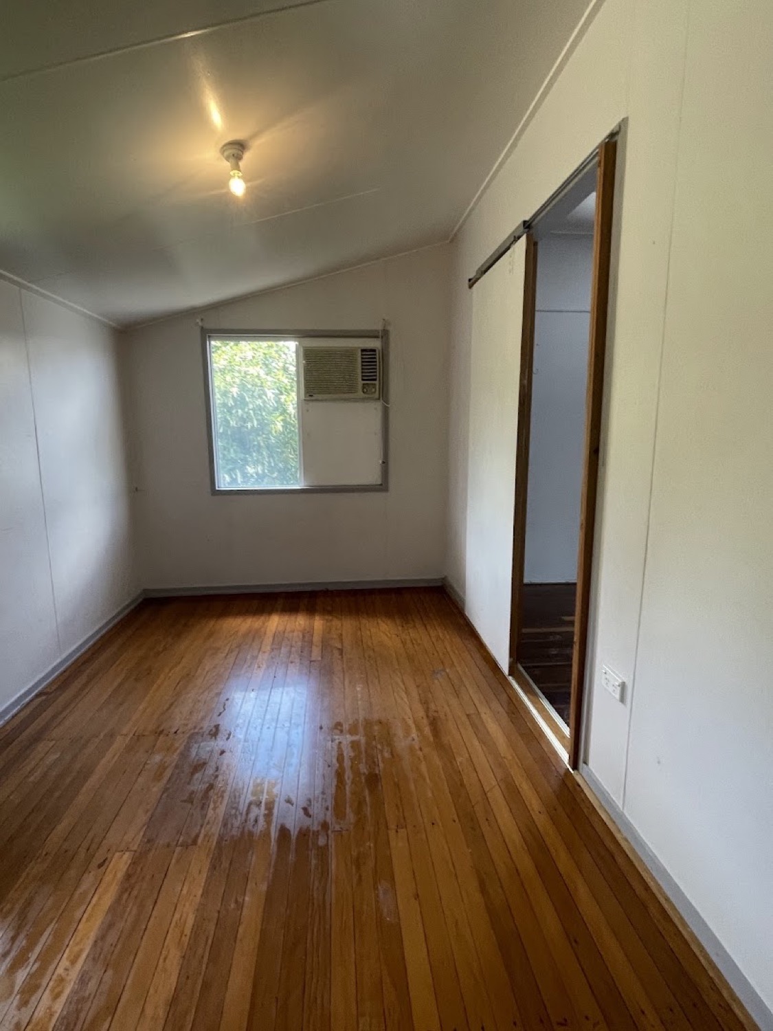 A hallway with polished timber boards and a window at the end