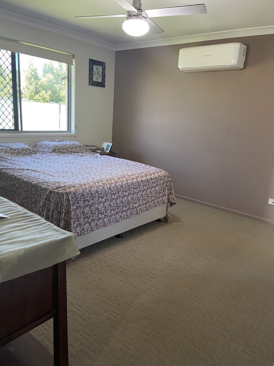 A carpeted bedroom with a bed, window and wall-mounted air conditioner